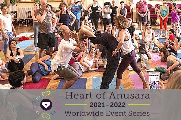 anusara teachers in italy assist a student in a standing drop back backbend while a samavesha crowd watches