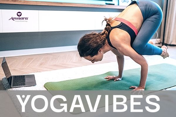 donna in posa di corvo pratica anusara yoga online sul suo computer con yogavibes