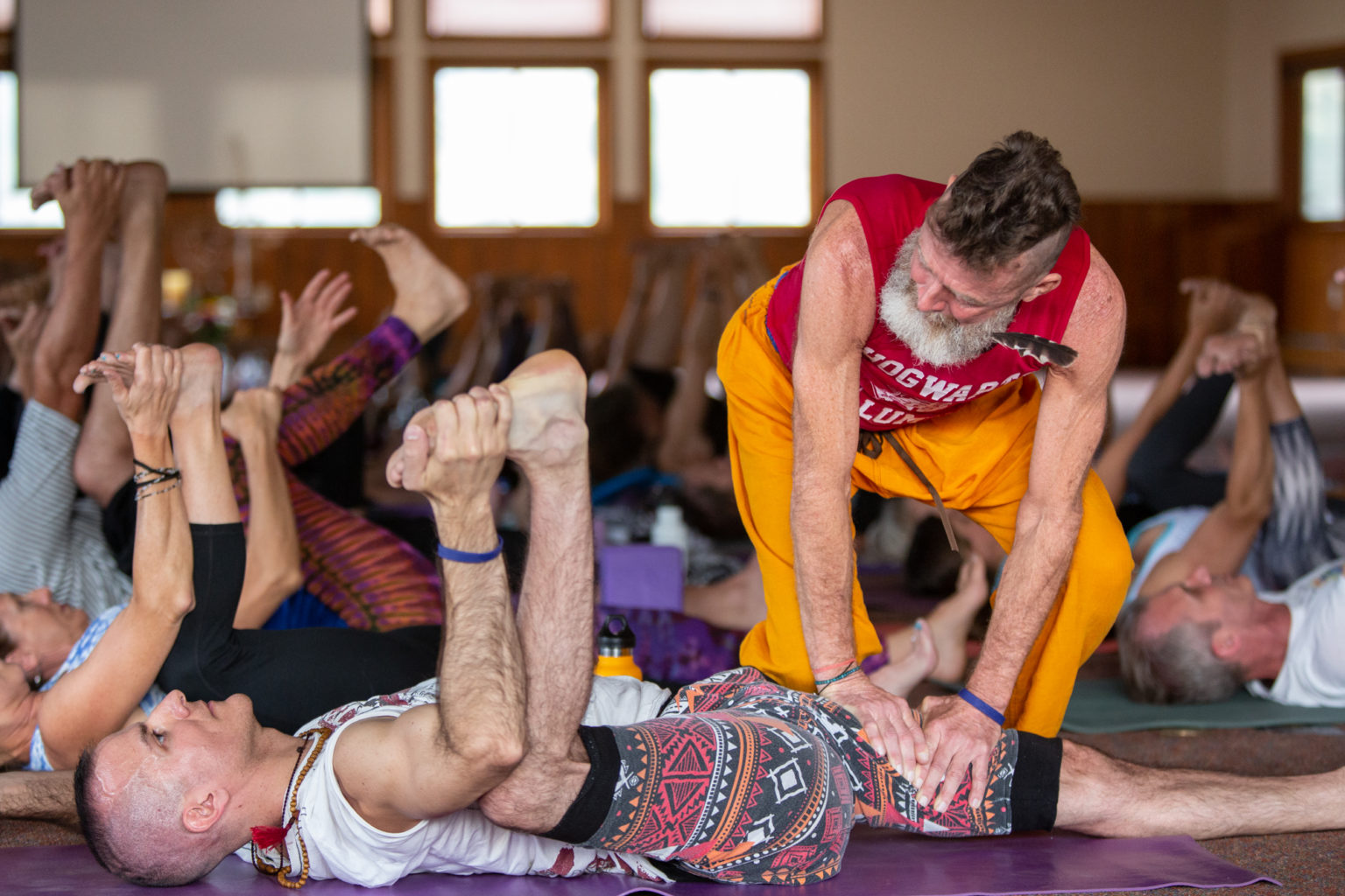 Jaye Martin, profesora de yoga de Anusara, ayuda a un estudiante en la postura del bebé medio feliz