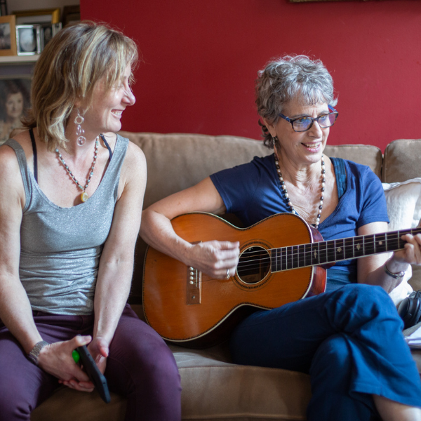 Tiffany Wood and Jacalyn Prete, Certified Anusara teachers sing together and play guitar
