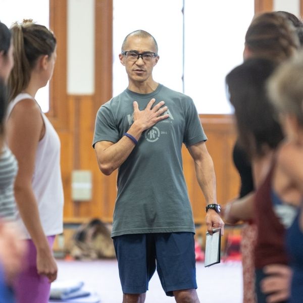 Anusara erfahrener zertifizierter Anusara Yoga Lehrer Keric Morinaga berührt sein Herz, als er die universellen Ausrichtungsprinzipien von Anusara teilt