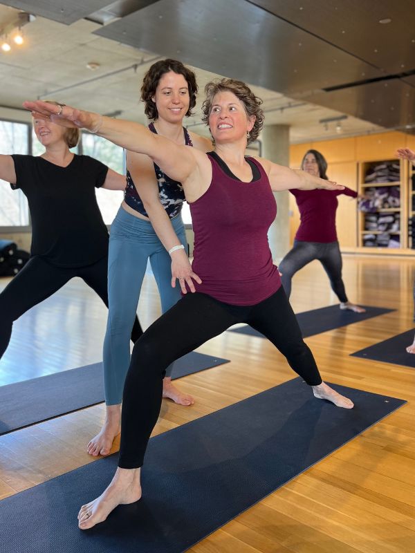 julia pearring ayuda a kim friedman en guerrero 2 anusara yoga pose centrándose en la energía muscular